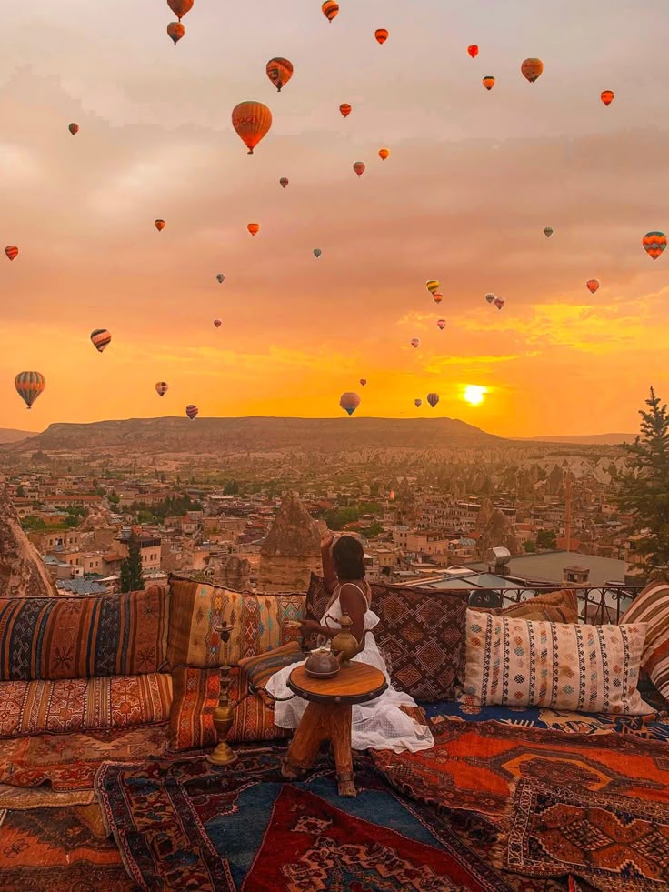 Terraza con alfombras y globos aerostáticos al atardecer en Capadocia