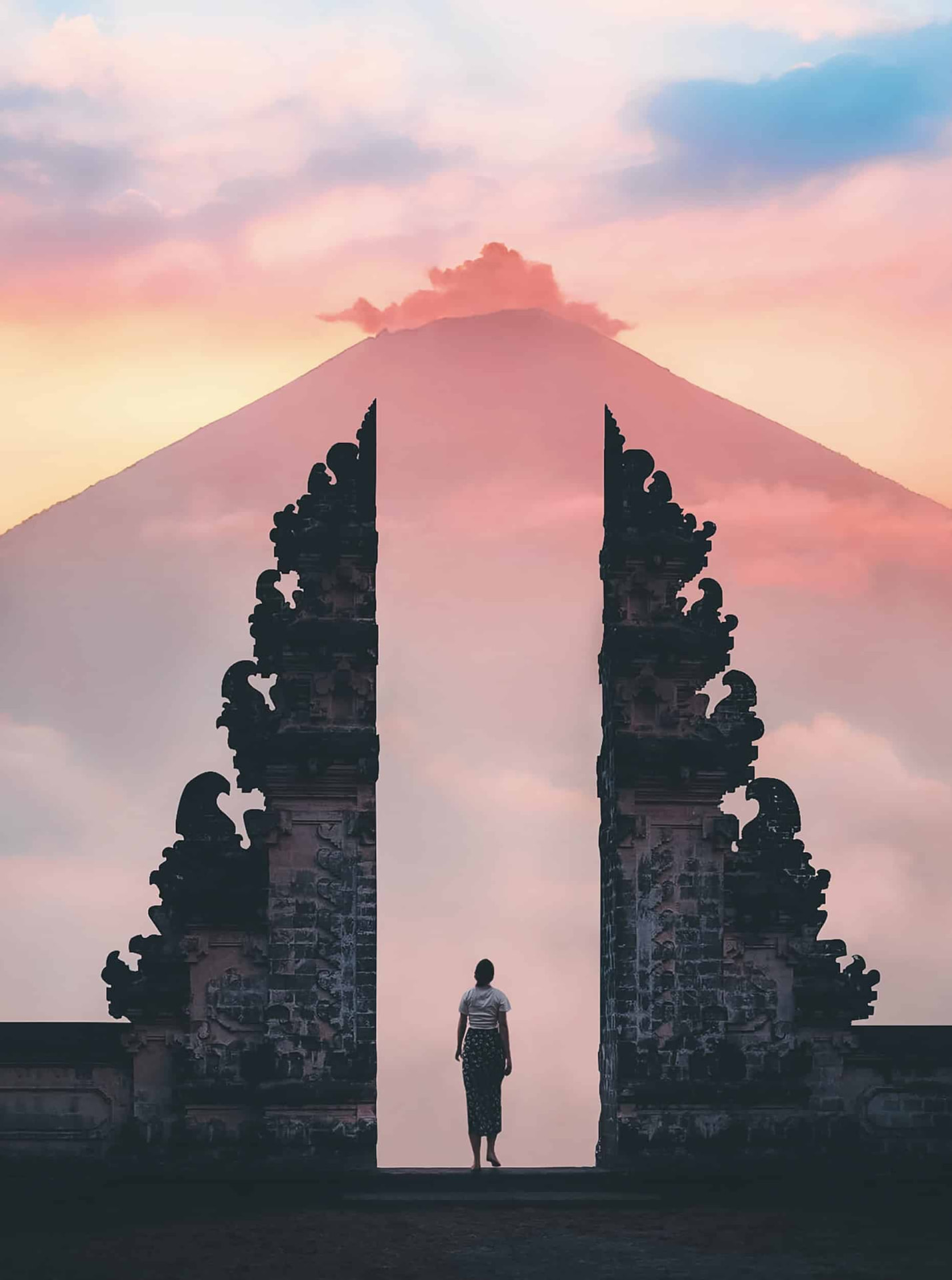 Templo balinés con el volcán al fondo y cielo rosado al amanecer