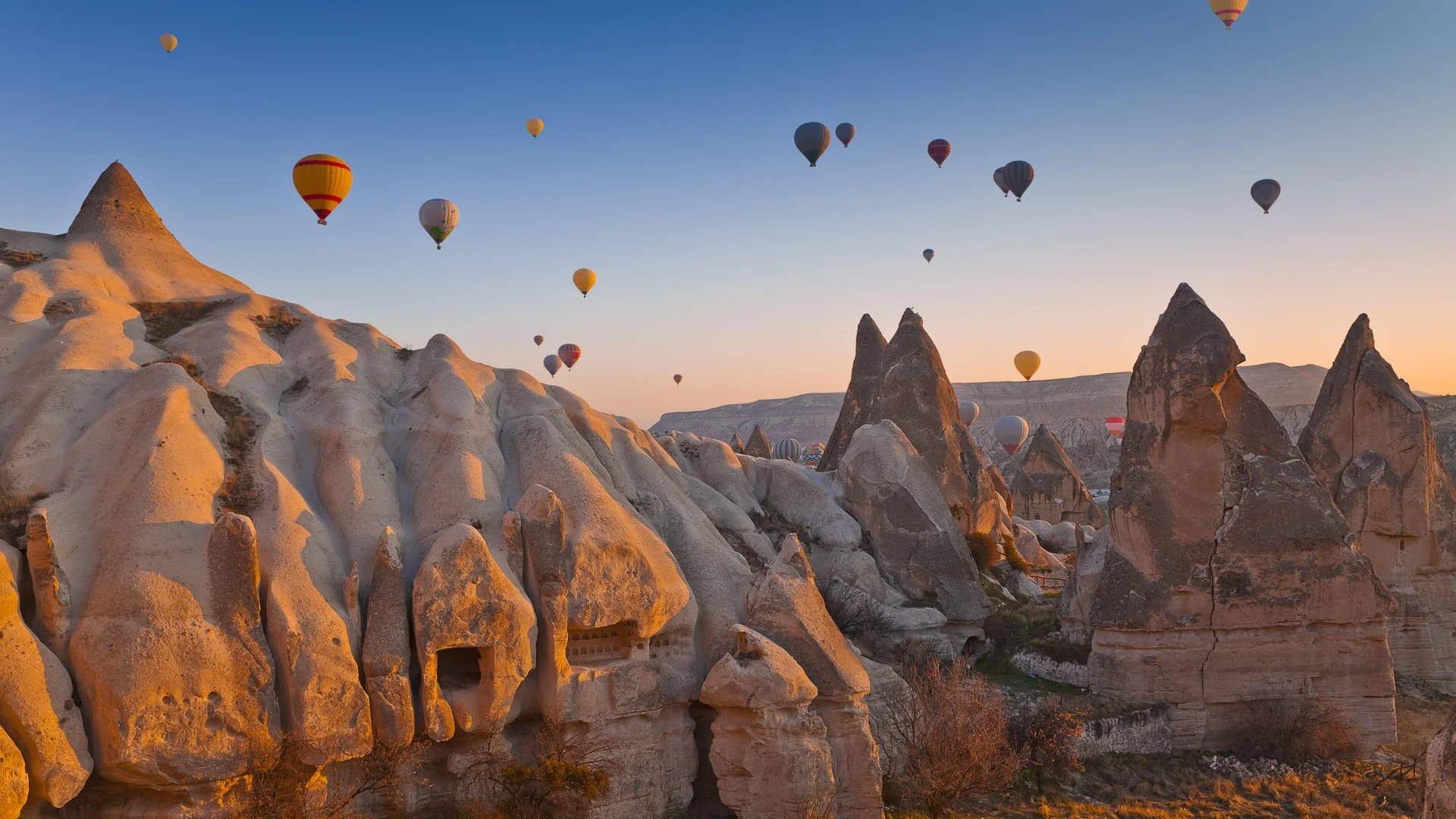 Formaciones rocosas de Capadocia con globos aerostáticos al amanecer